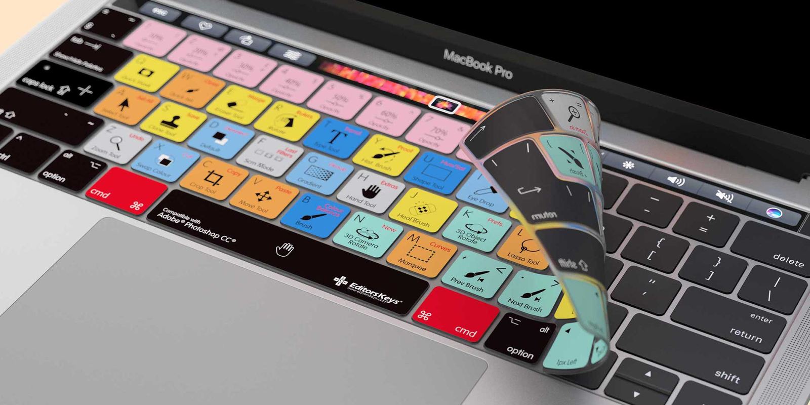 A close-up of a MacBook Pro keyboard covered with a colorful custom shortcut keycap skin, with a curled-up sample of the keycap sheet shown in front. The skin features various pastel and bright colors for different keyboard keys from Editors Keys